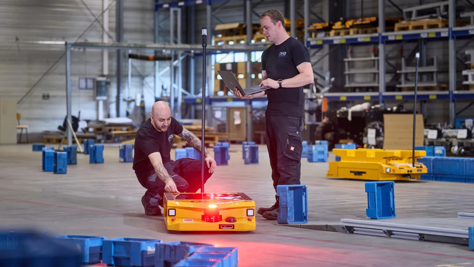 Inbetriebnahme eines autonomen mobilen Robotersystems, ein Mitarbeiter am Fahrzeug, einer am Laptop
