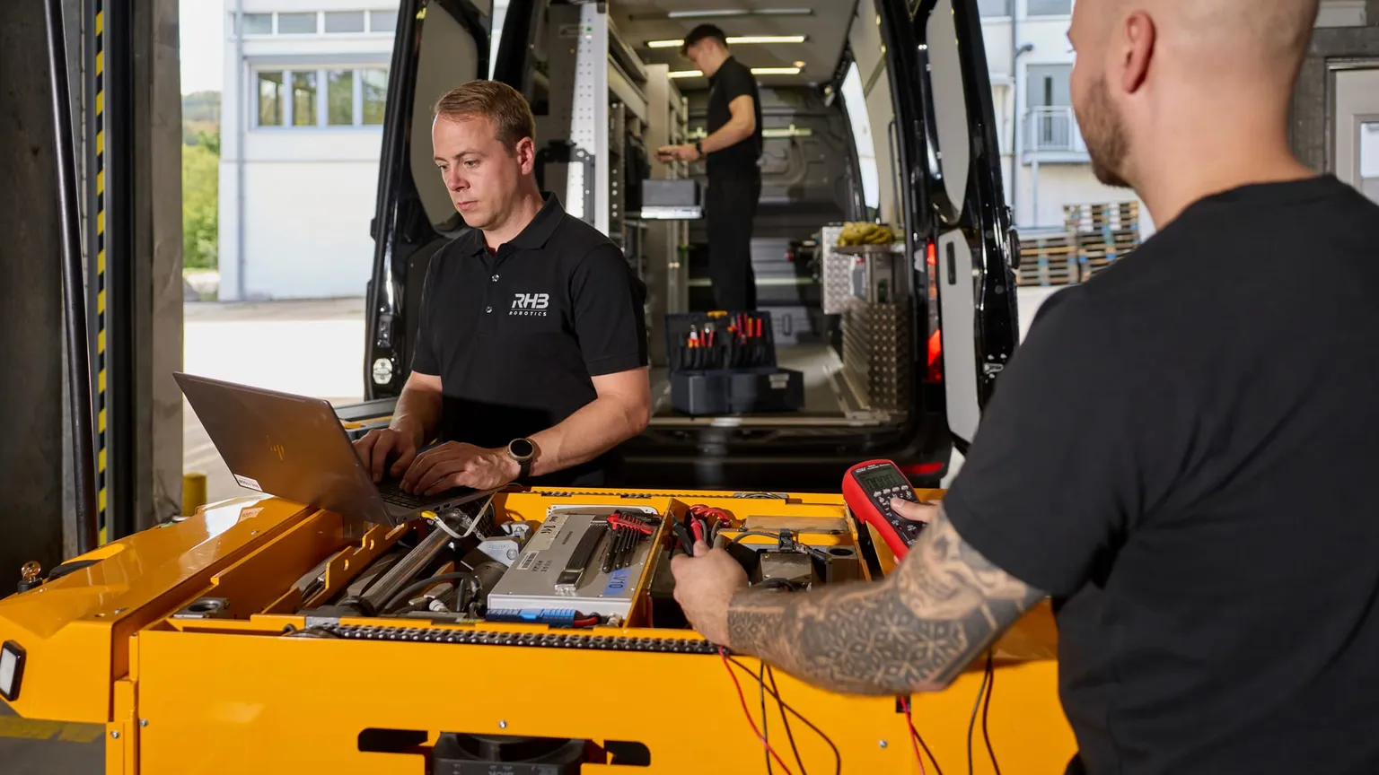 Vor-Ort-Service am geöffneten Fahrzeug, Diagnose mit Laptop und Messgerät, dahinter das Servicefahrzeug