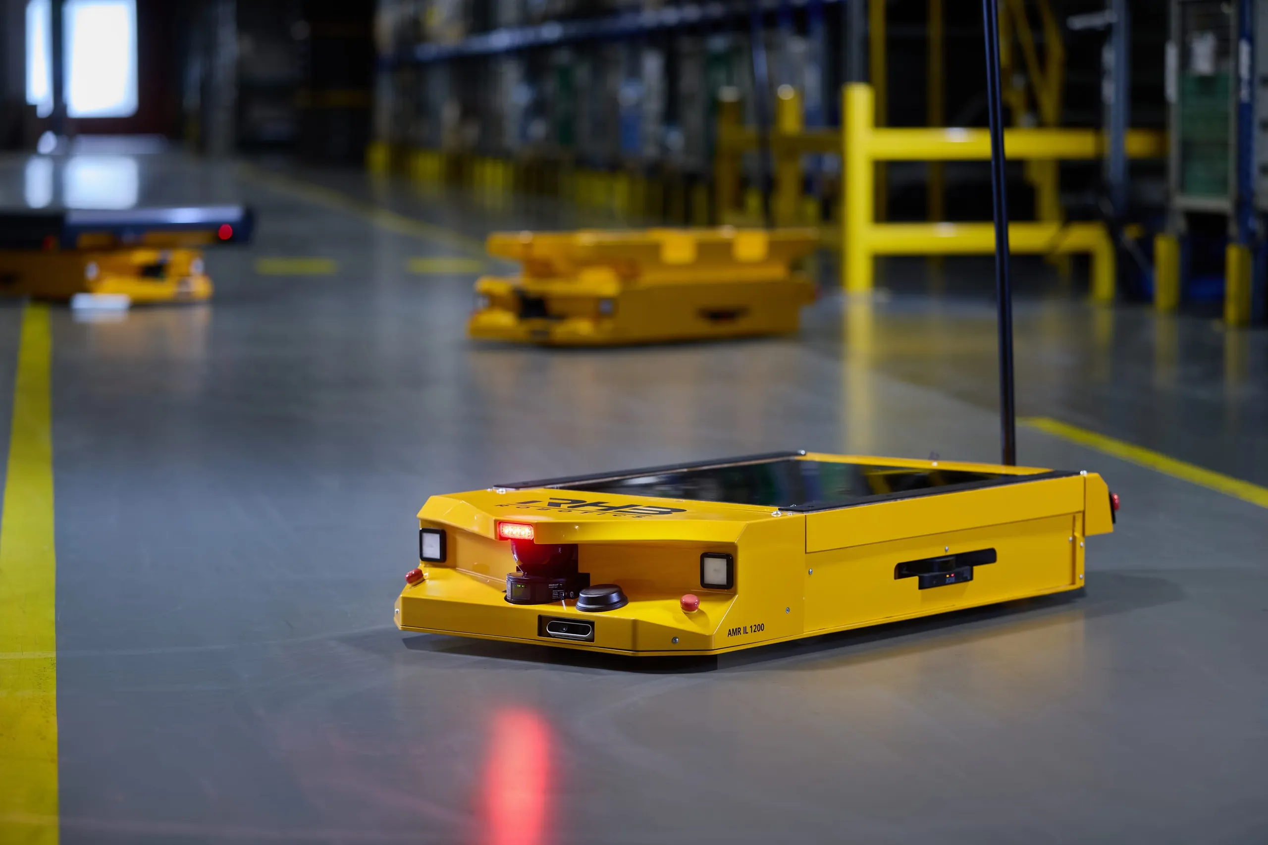 Autonomes mobiles Robotersystem AMR IL 1200 auf dem Fahrweg in der Halle, dahinter zwei weitere Fahrzeuge
